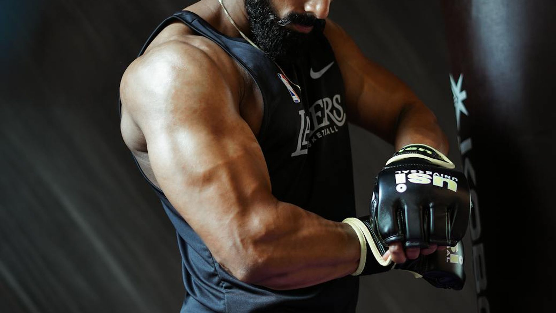 Man in a focused powerful stance in a dark minimalist gym.