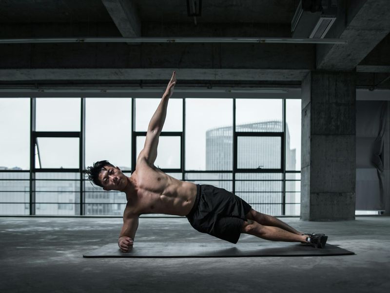Man performing a controlled bodyweight exercise on a mat.